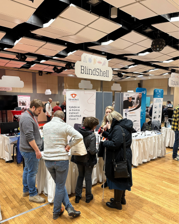 Besucher versammelten sich am BlindShell-Stand auf der INSPO-Konferenz für assistive Technologien, hörten Produktvorführungen an und stellten Fragen in einer gut besuchten Ausstellungshalle.